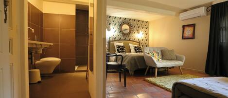 Una habitación de hotel con baño, una cama, un sofá y una mesita.