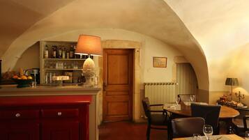 A cozy dining area with a wooden table, chairs, and a bar area with shelves of bottles and glasses.