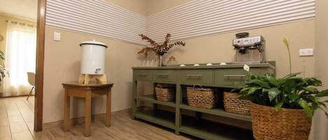 A kitchen with a coffee machine, a water dispenser, and wicker baskets on shelves.