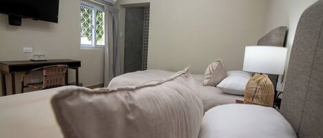 Une chambre d’hôtel avec deux lits, un bureau, une chaise, une télévision et un appareil de climatisation.