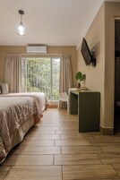 Un dormitorio con cama, escritorio, silla y ventana con cortinas.