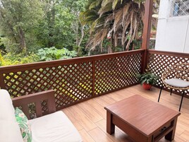 Eine Holzterrasse mit Tisch und Stühlen, umgeben von einem Holzzapfen und Blick auf einen üppigen Garten.
