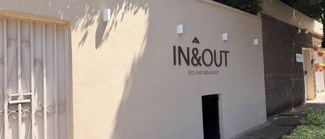 Un bâtiment portant une enseigne indiquant « IN&OUT BED AND BREAKFAST », ce qui signifie qu’il propose un service de chambre d’hôtes.