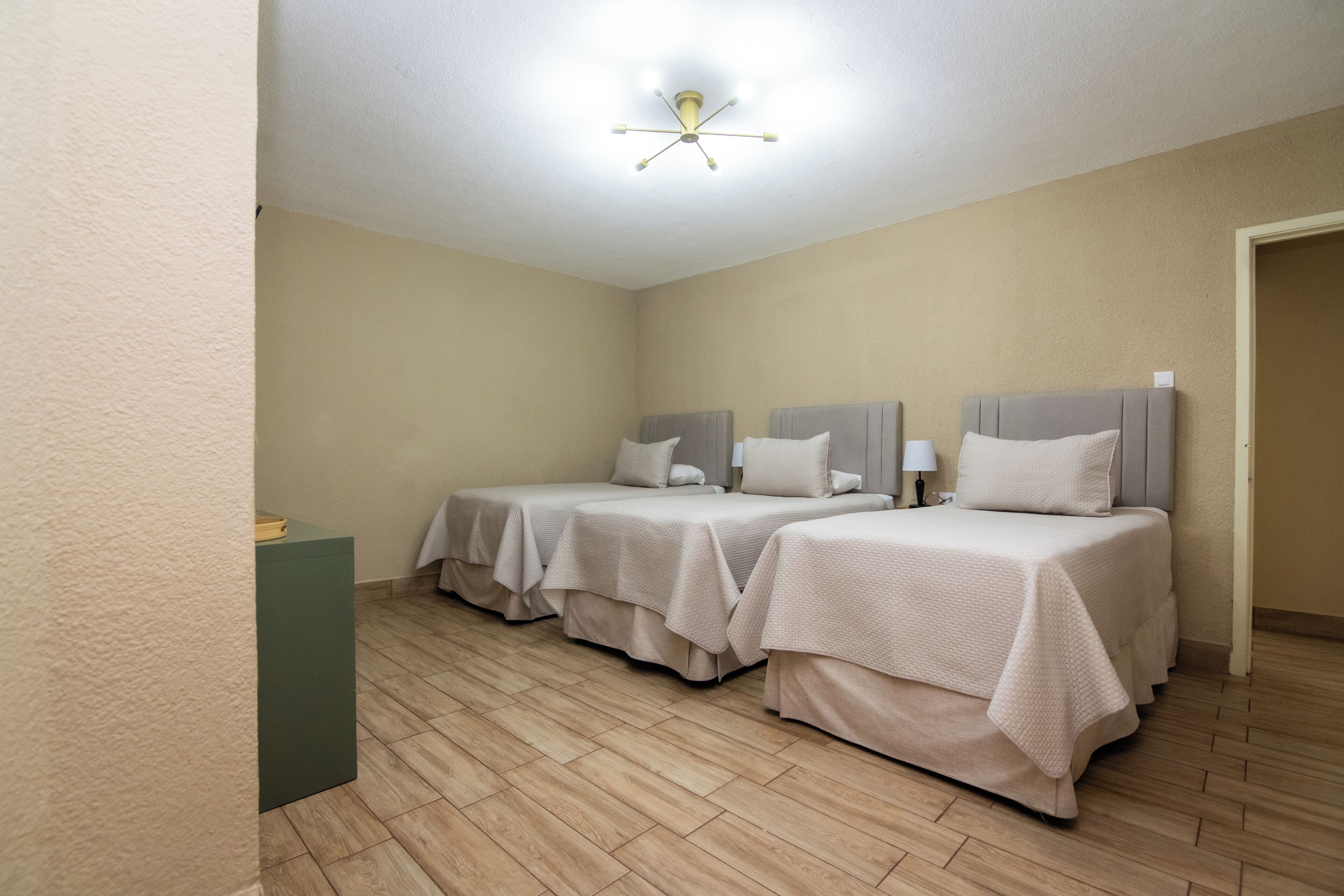Ein Hotelzimmer mit zwei Betten, einer Deckenlampe und Holzboden.