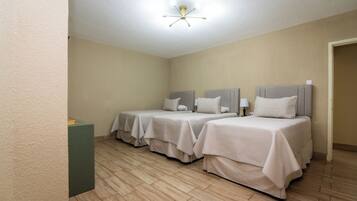 Ein Hotelzimmer mit zwei Betten, einer Deckenlampe und Holzboden.