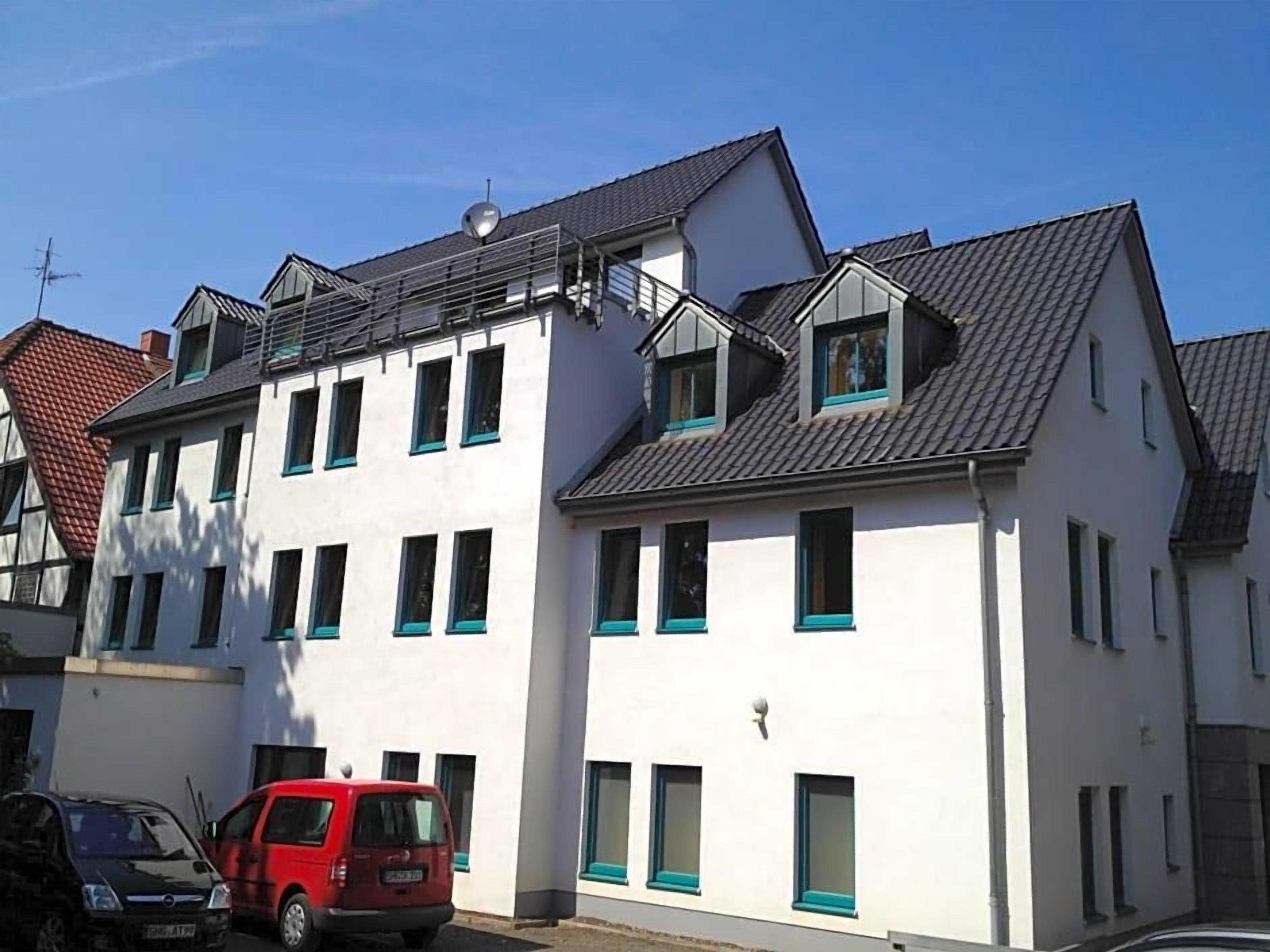 A multi-story residential building with a flat roof, multiple windows, and a satellite dish.