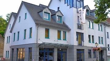 A hotel with a modern design, featuring a prominent entrance with a glass canopy, multiple windows, and a sign indicating it is a hotel.