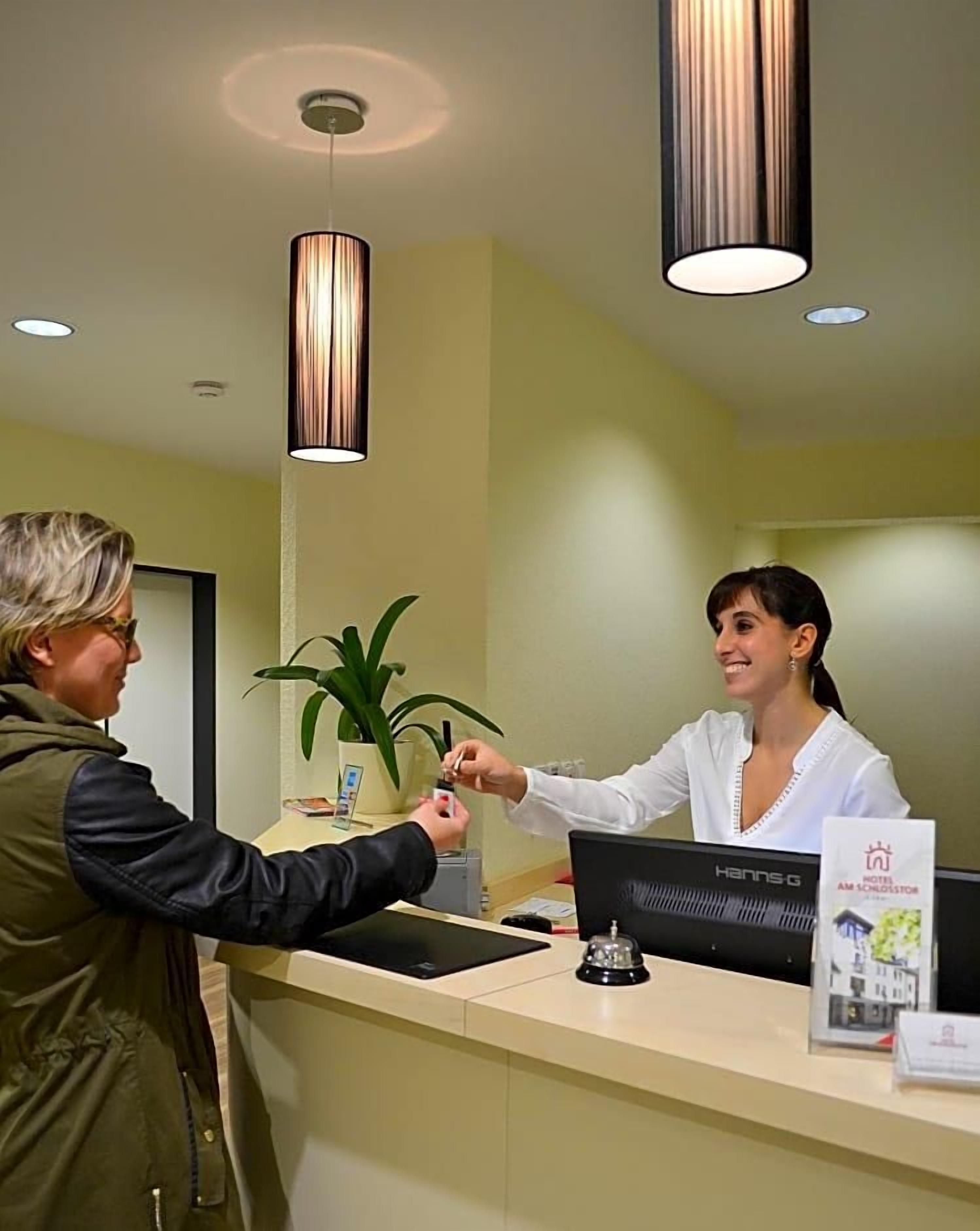 A reception desk with a computer, a plant, and a framed picture on the wall.