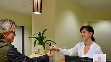 A reception desk with a computer, a plant, and a framed picture on the wall.