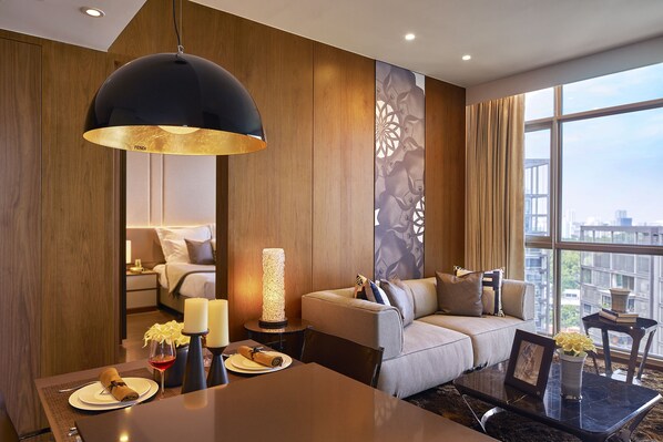 Une chambre d’hôtel moderne dotée d’un canapé, d’une table à manger et d’une grande fenêtre donnant sur la ville.