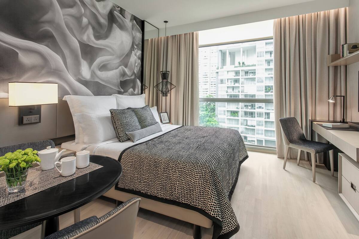 Een moderne hotelkamer met een groot bed, een bureau en uitzicht op de stad.
