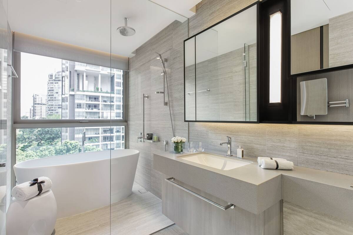 Een moderne badkamer met een groot raam, een badkuip, een douche en een wastafel met spiegel.
