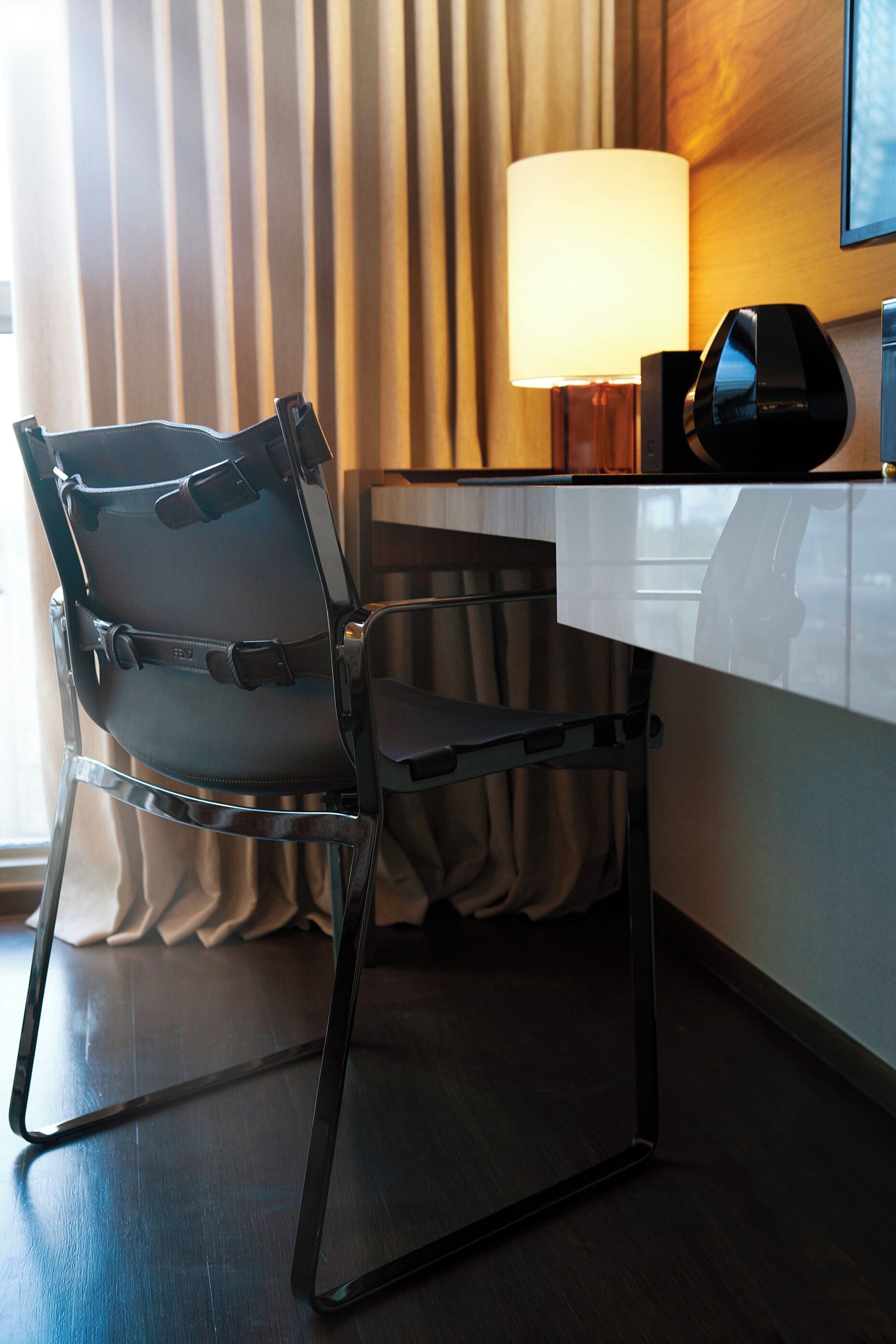 Une chambre d’hôtel moderne équipée d’un bureau, d’une chaise, d’une lampe et d’un tableau encadré au mur.