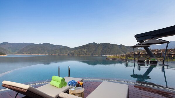 An infinity pool with a view of mountains and a body of water. - Crowne Plaza Hangzhou Thousand Island Lake by IHG (Hangzhou)