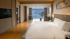 A hotel room with a large bed, a television, a desk, and a view of the sea. - Crowne Plaza Hangzhou Thousand Island Lake by IHG (Hangzhou)