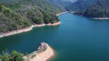 A river surrounded by forested hills with a small dock and a boat.