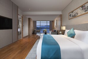 Una habitación de hotel moderna con una cama grande, un televisor de pantalla plana, un escritorio y vistas a las montañas a través de la ventana.
