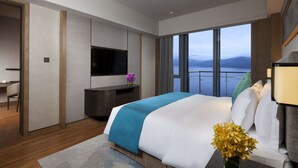 A modern hotel room with a large bed, a desk, a flat-screen TV, and a view of the sea. - Crowne Plaza Hangzhou Thousand Island Lake by IHG (Hangzhou)
