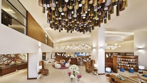 A spacious lobby with a high ceiling, multiple seating areas, and a central floral arrangement. - Courtyard by Marriott Riyadh Olaya (Riyadh)