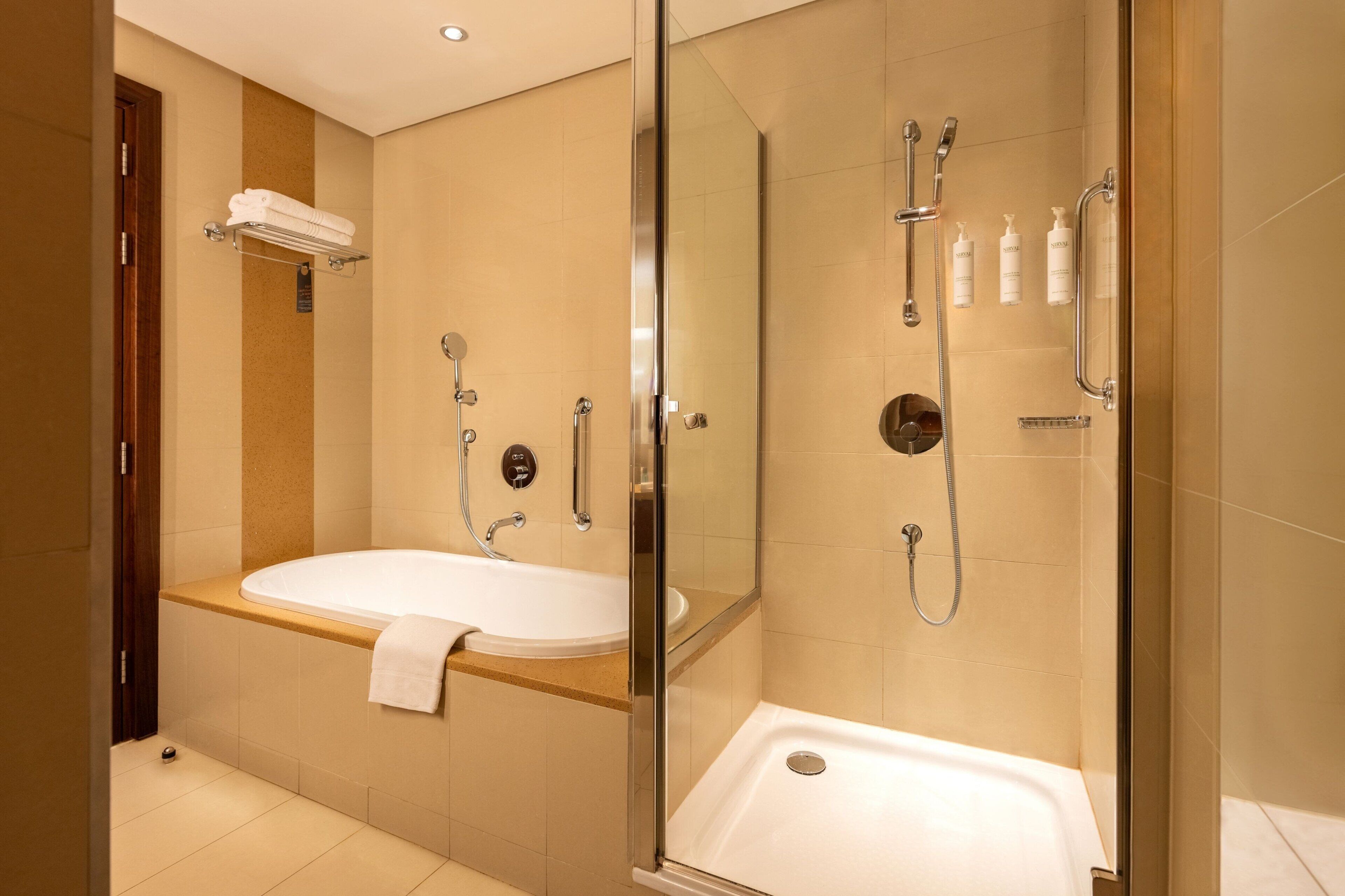 Un baño moderno con ducha acristalada, bañera independiente y tocador con toallero.