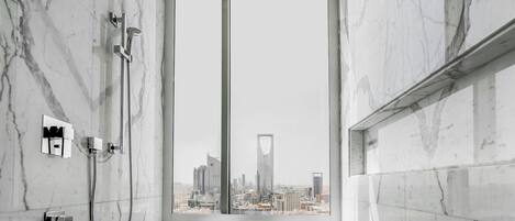 A bathroom with a large window, a shower, and a view of a cityscape.