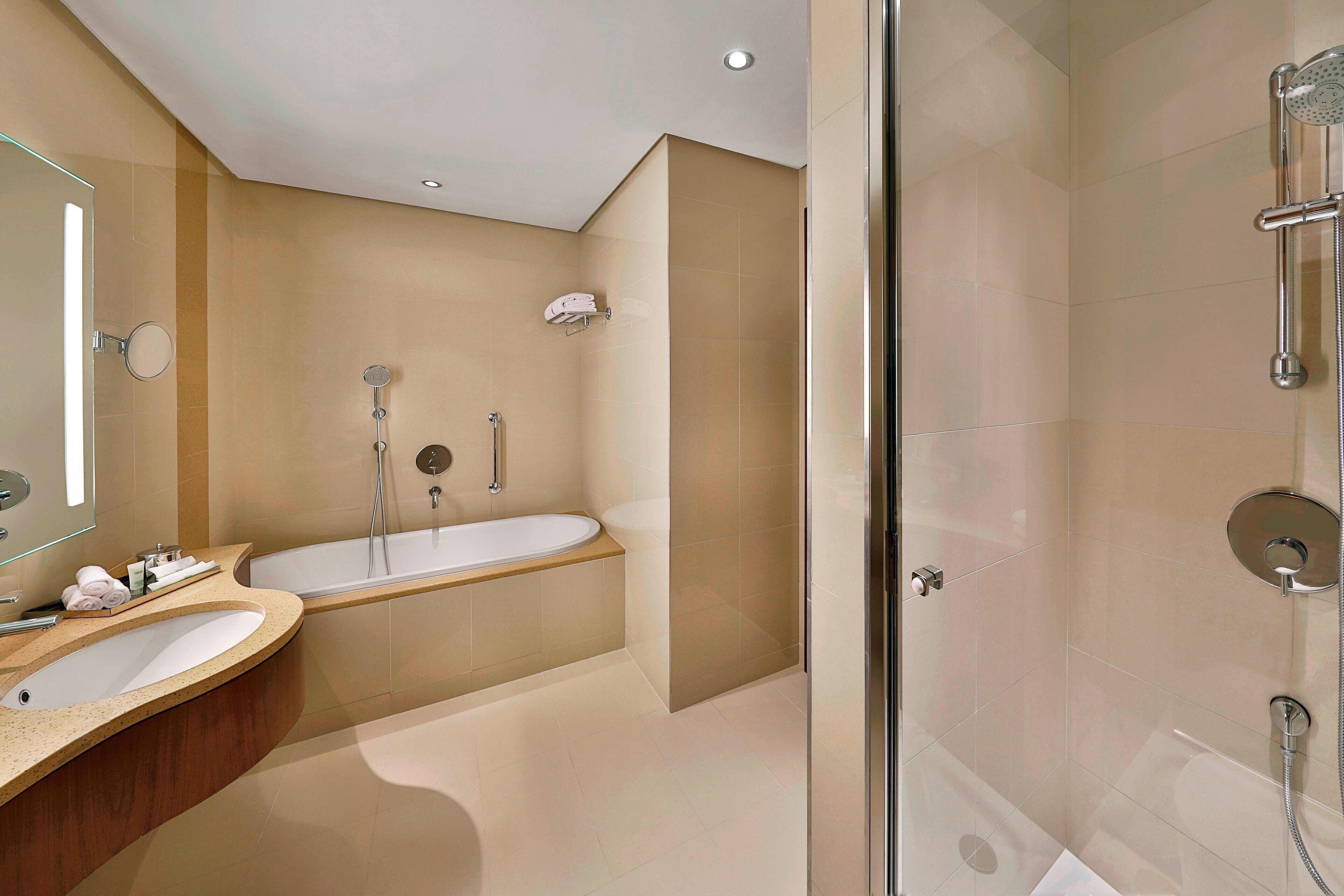 A modern bathroom with a glass-enclosed shower, a freestanding bathtub, and a vanity with a mirror.
