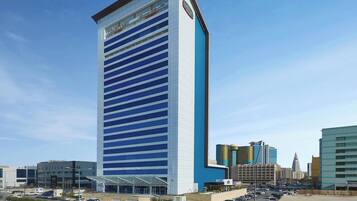 A tall hotel with a modern design, featuring a prominent entrance and a large parking area.