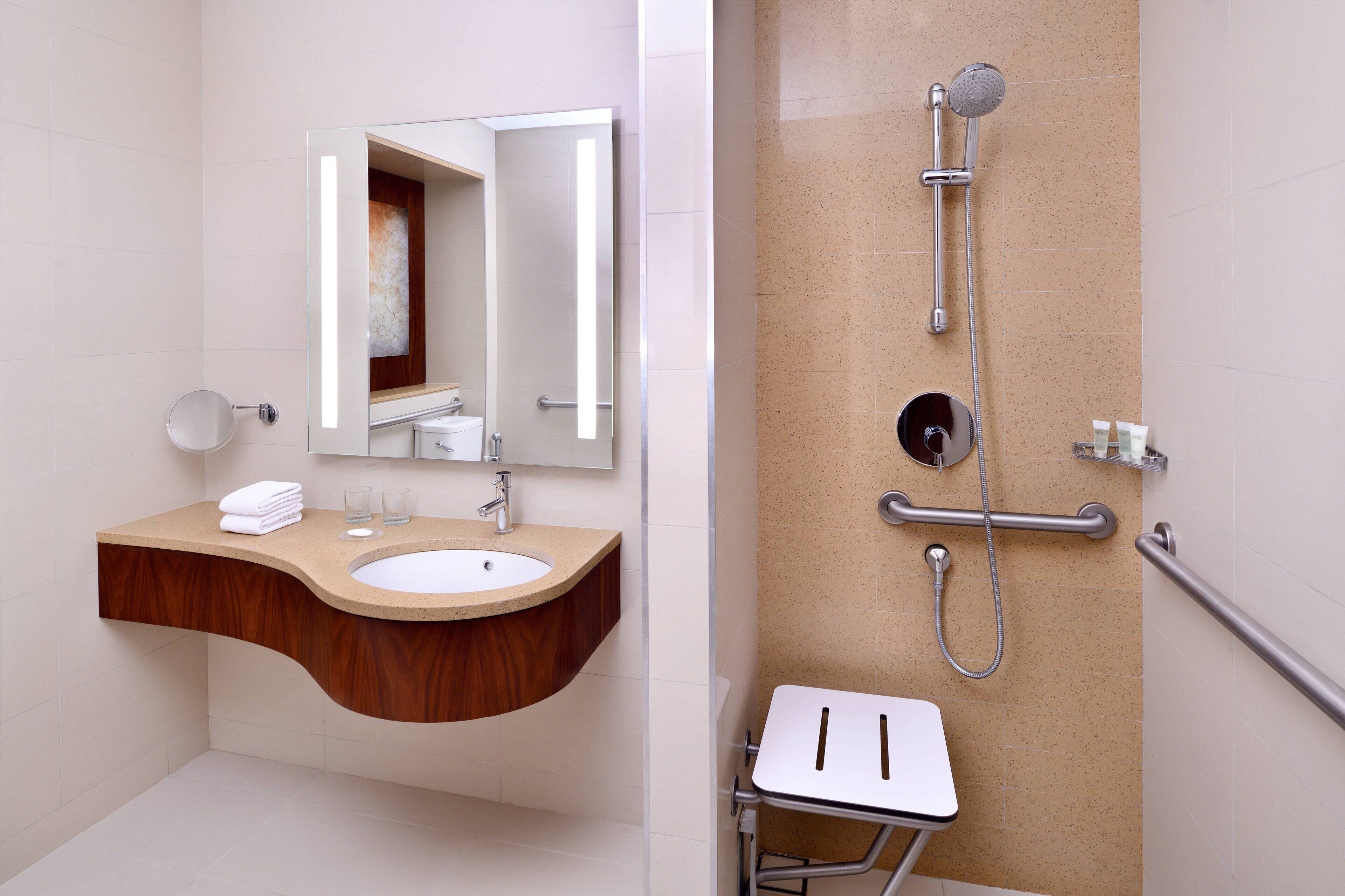 A modern bathroom with a wooden vanity, a sink, a mirror, and a shower with a handheld showerhead.