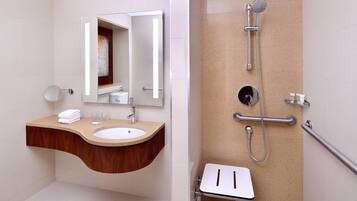 A modern bathroom with a wooden vanity, a sink, a mirror, and a shower with a handheld showerhead.