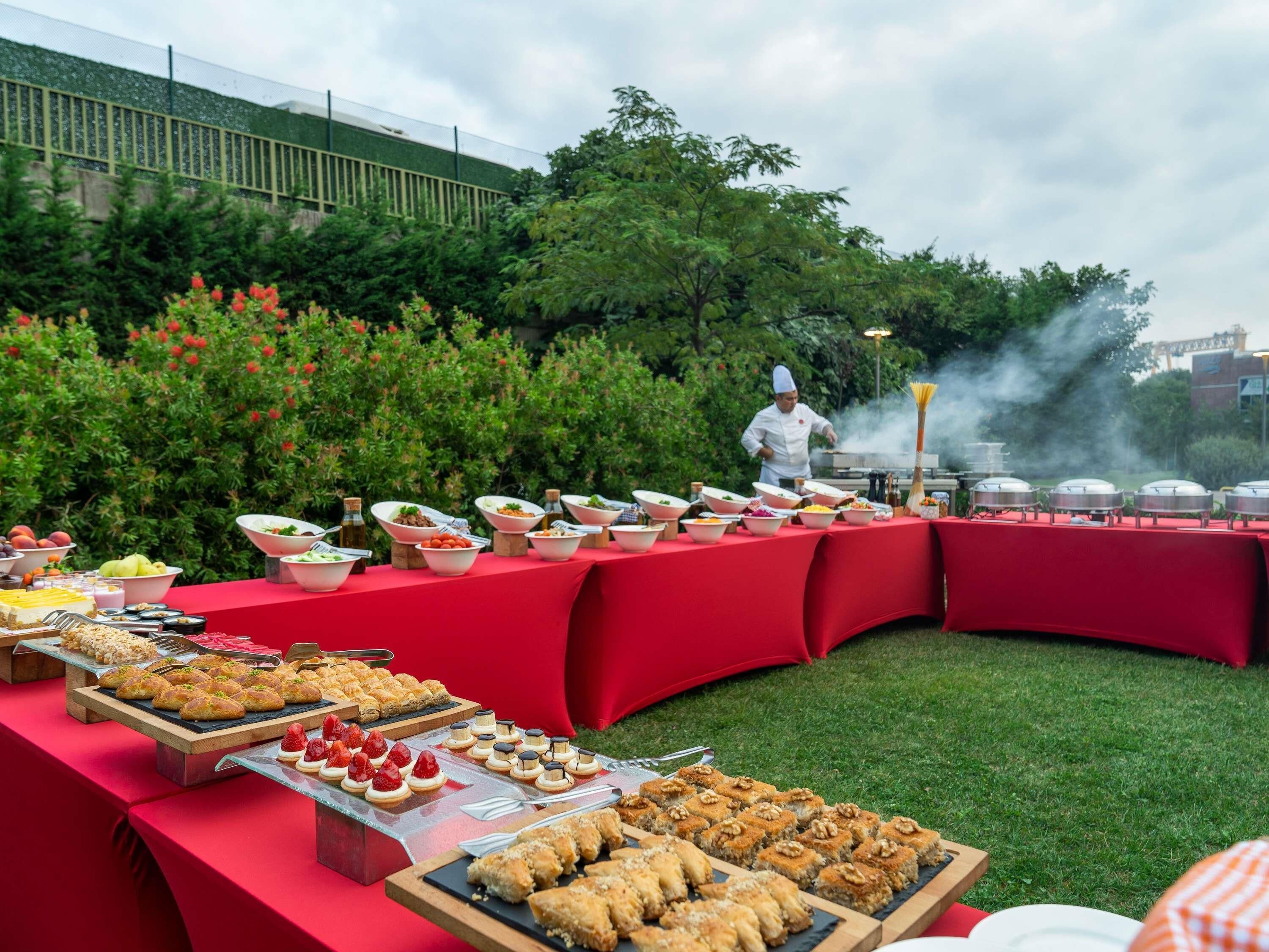 An outdoor buffet with various food items and a chef preparing food.