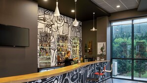 A modern bar area with a curved counter, bar stools, and a large window offering a view of greenery. - Ibis Istanbul Tuzla (Tuzla)
