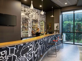 Un área de bar moderna con una barra curva, taburetes y un ventanal con vistas a zonas verdes.
