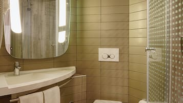 Un baño moderno con un espejo grande, un lavabo, un inodoro y una zona de ducha.
