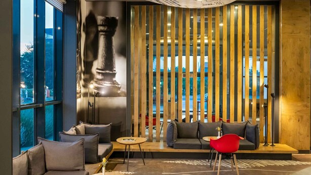 A modern lounge area with a curved ceiling decorated with sketches and notes, a large chess piece mural, and a view through large windows. - Ibis Istanbul Tuzla (Tuzla)