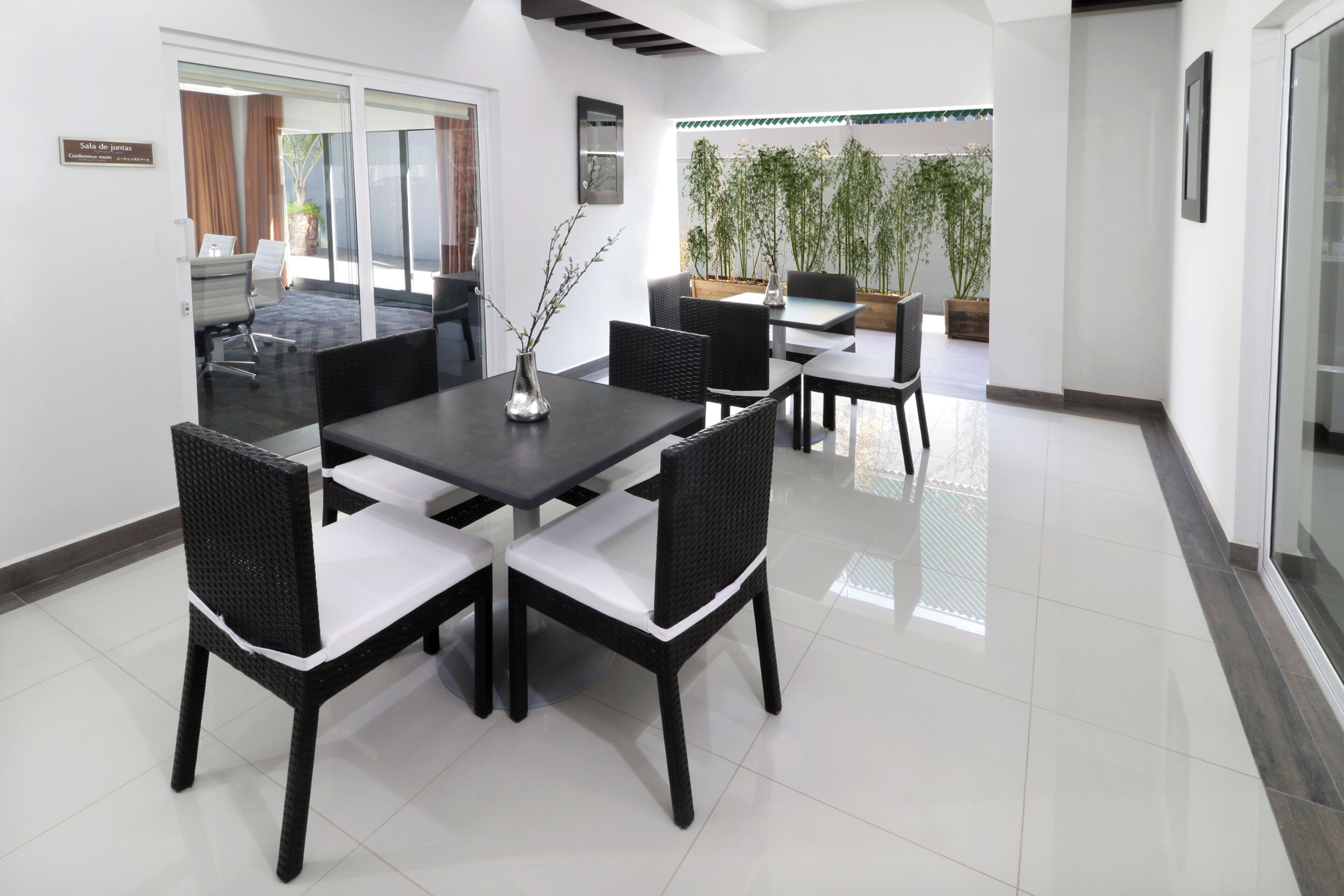 Une salle de conférence équipée d’une table et de chaises, d’un vase orné de branches et offrant une vue sur l’extérieur.