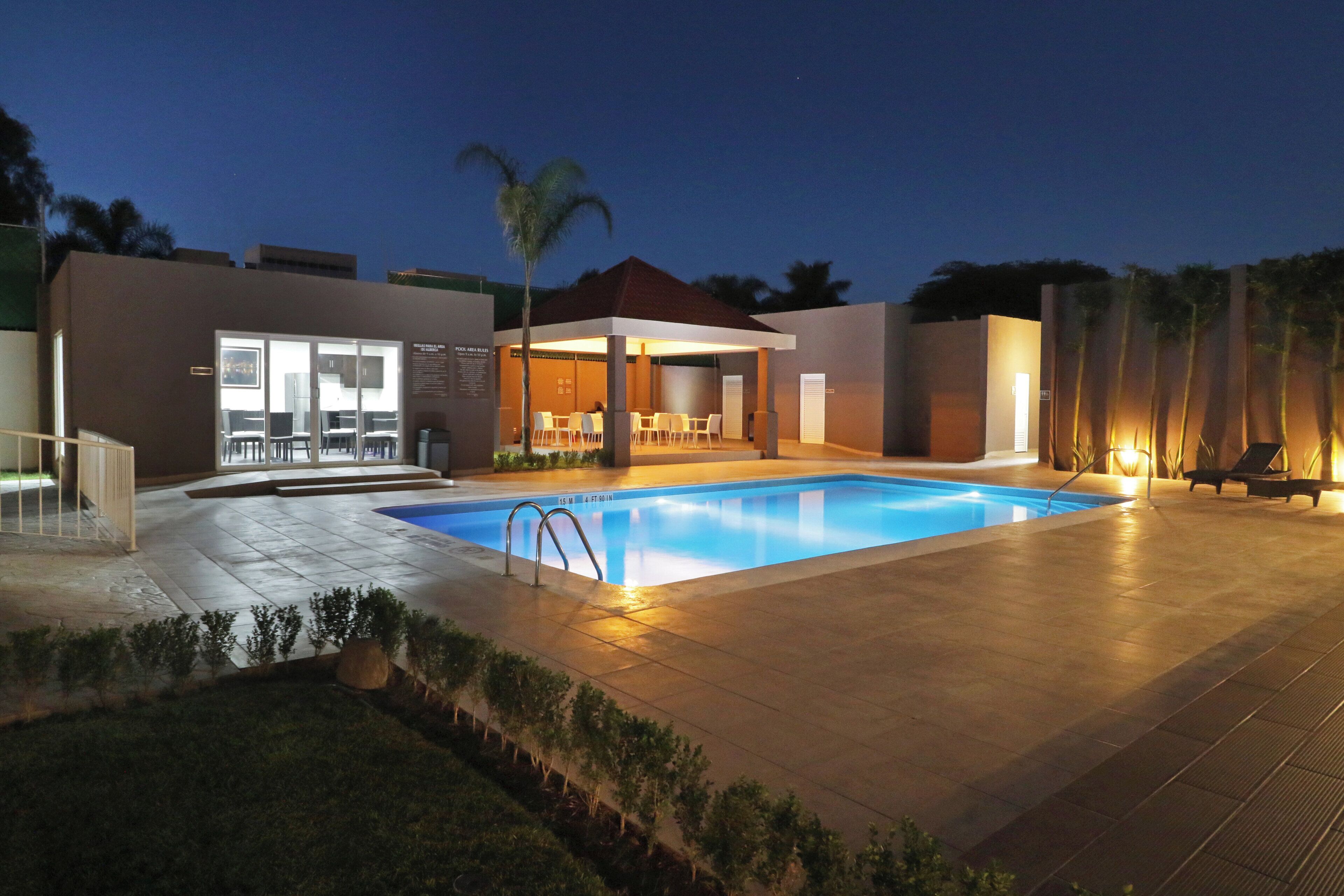 Una piscina con zona cubierta, asientos y vistas del paisaje circundante.