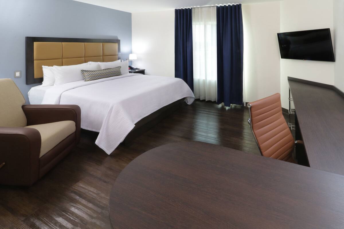 Een hotelkamer met een groot bed, een bank, een stoel, een televisie en een bureau.