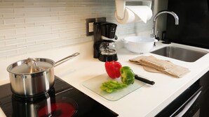 Une cuisine équipée d’une cuisinière, d’une machine à café, d’un évier et d’une planche à découper avec des légumes.