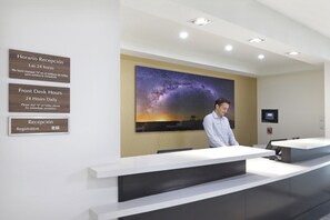 A reception desk with a galaxy-themed wall mural, a fire alarm, and a digital screen.