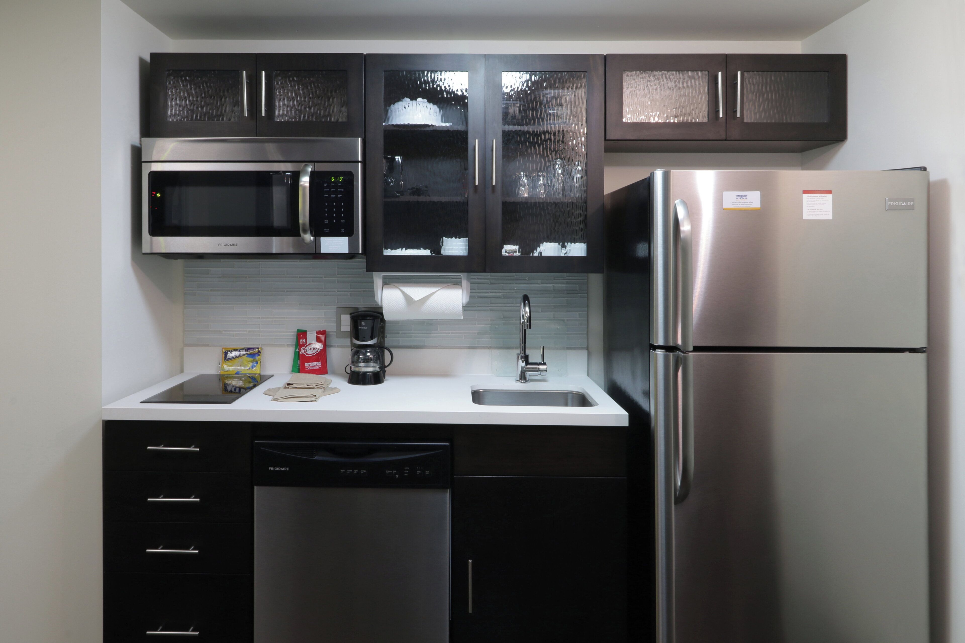 Cocina moderna con electrodomésticos de acero inoxidable, incluyendo microondas, cafetera y refrigerador.