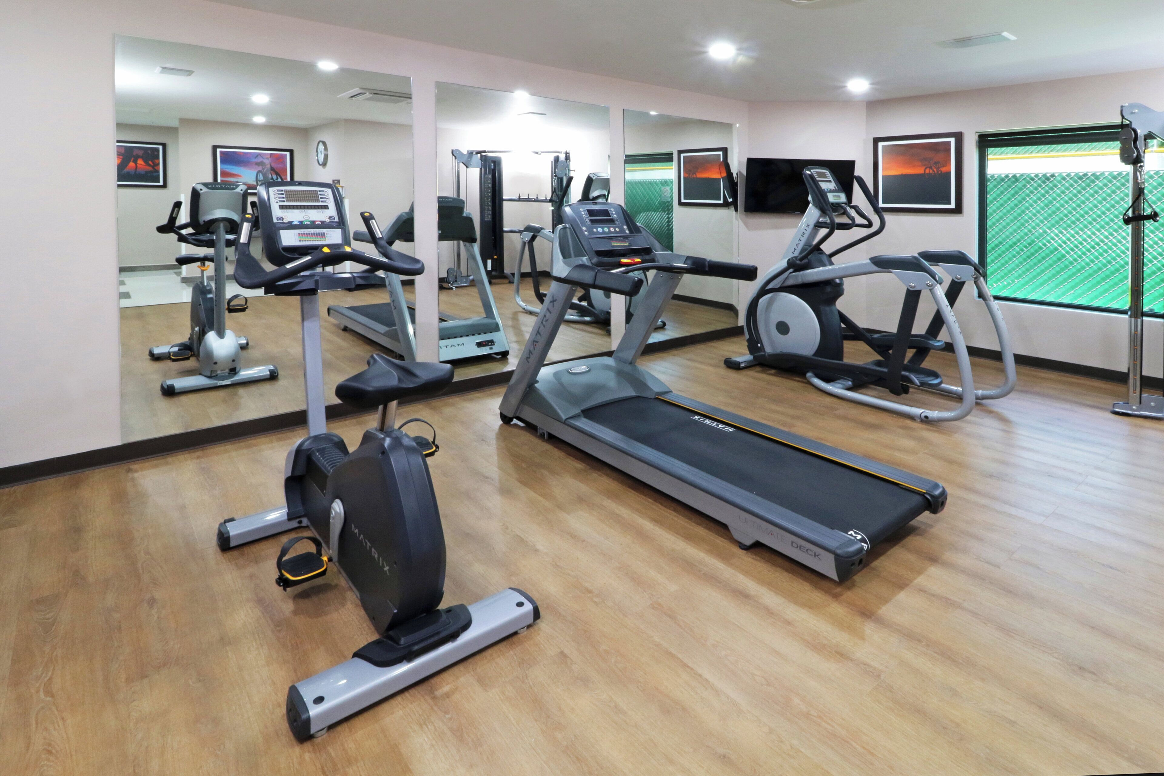 A gym with various exercise equipment including treadmills, stationary bikes, and elliptical machines.