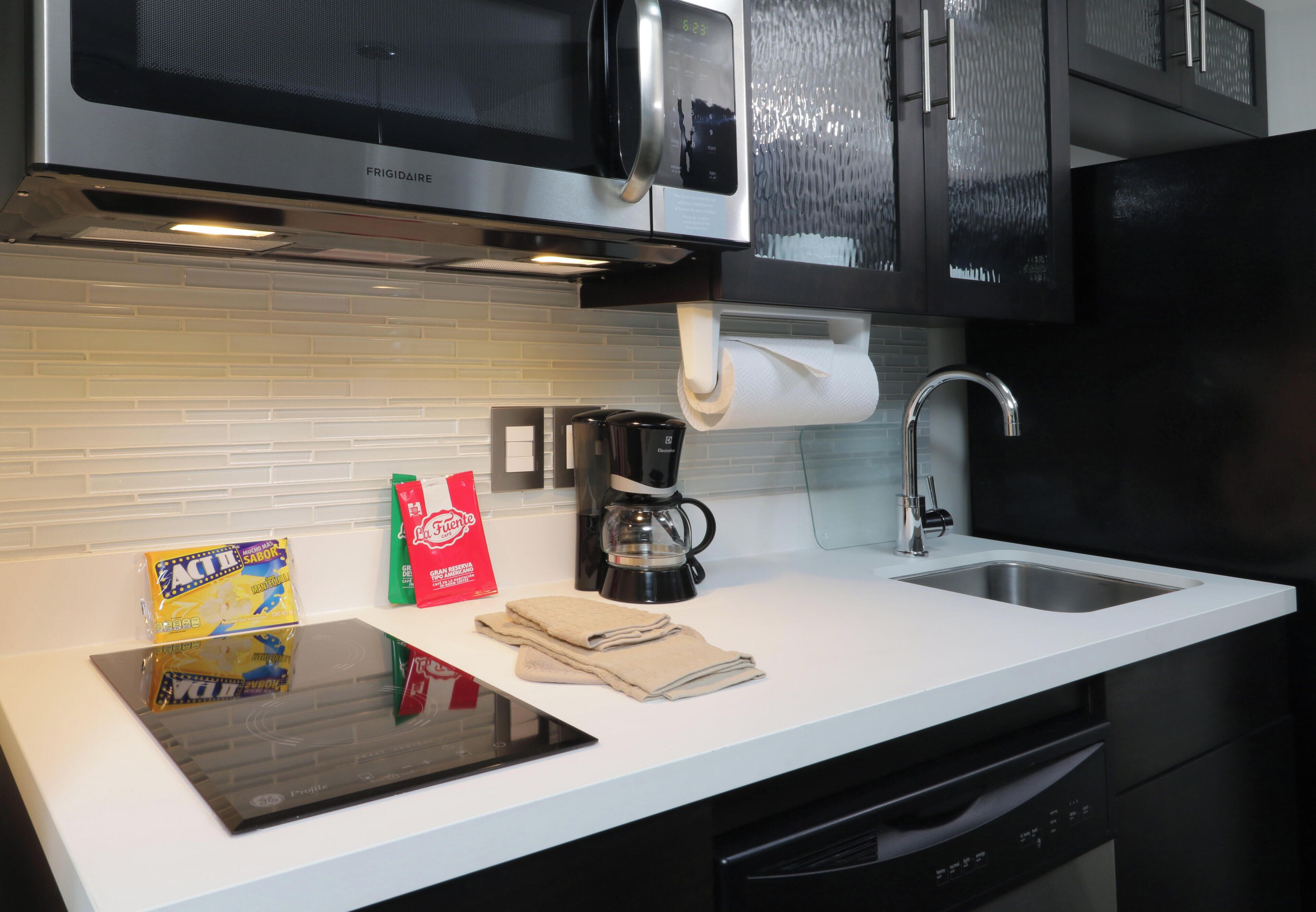 A kitchen with a microwave, coffee maker, and a tablet on the counter.