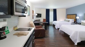 Une chambre d’hôtel équipée d’une kitchenette, de deux lits, d’un bureau et d’une télévision.