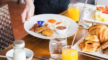 A breakfast tray with eggs, bacon, croissants, and juice.