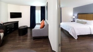 Ein Hotelzimmer mit Bett, Sofa, Fernseher, Schreibtisch und Stuhl.