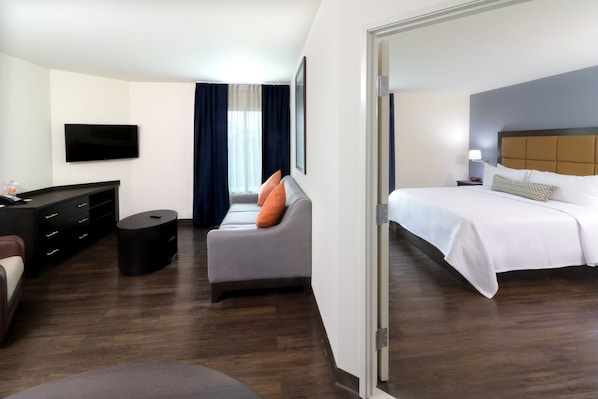 Ein Hotelzimmer mit Bett, Sofa, Fernseher, Schreibtisch und Stuhl.