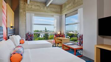 A hotel room with two beds, a desk, and a TV.