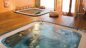 Un espace spa doté de planchers en bois, de deux bains à remous et d’arches en pierre.