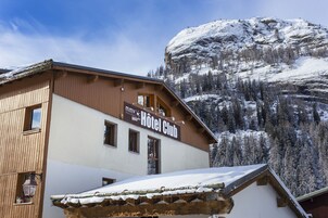 A wooden building with a sign for "Hotel Club" and a view of snow-covered mountains.