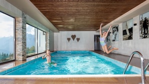 A modern indoor swimming pool with a wooden ceiling, large windows, and heart-shaped wall decorations. - Frieden (Pill)
